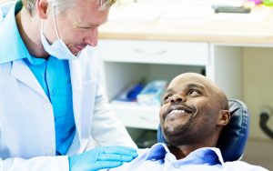 african american man in dental chair asking dentist if oral health affects overall health