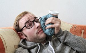 man on couch with ice pack after root canal