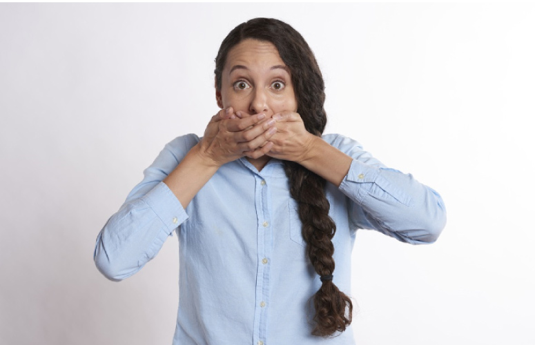 woman with a long braid covering her mouth with bad breath