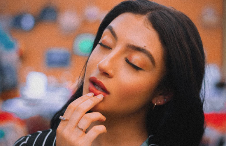 dark haired woman holding her lower lip concerned about teeth bleeding after flossing