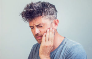 man holding his jaw with intense tooth pain