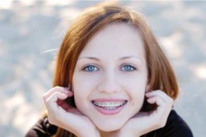 young girl leans on her hands and smiles to show off her braces