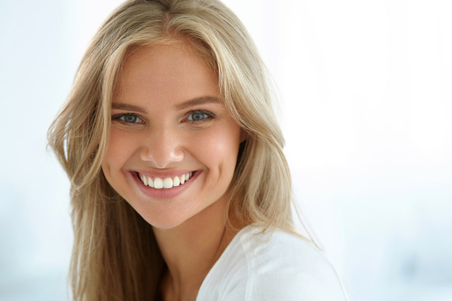 young blond woman smiles, showing off her white straight teeth