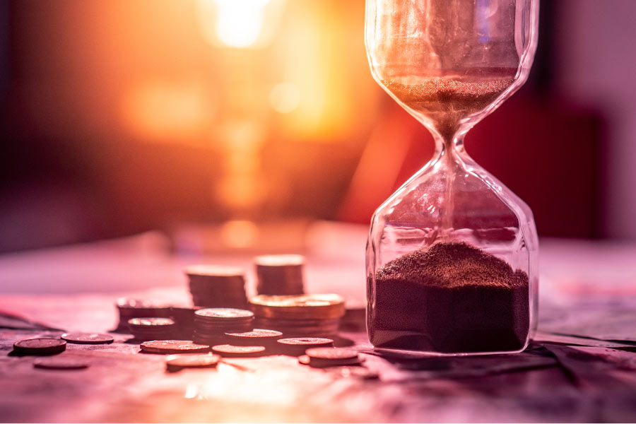 hourglass next to stacks of coins