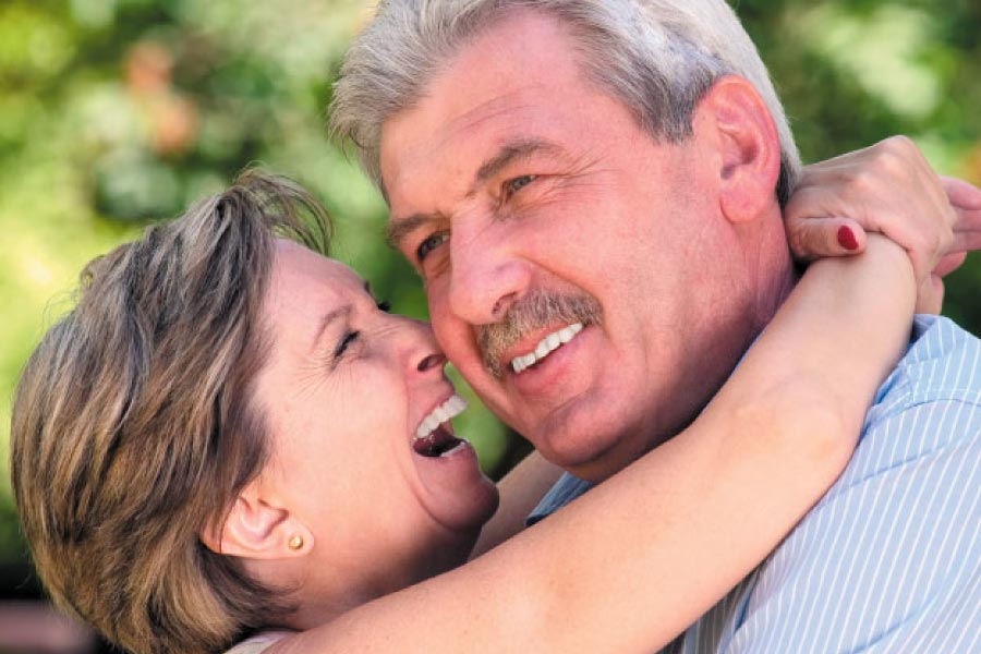 senior couple hug and smile after learning about dental crown aftercare