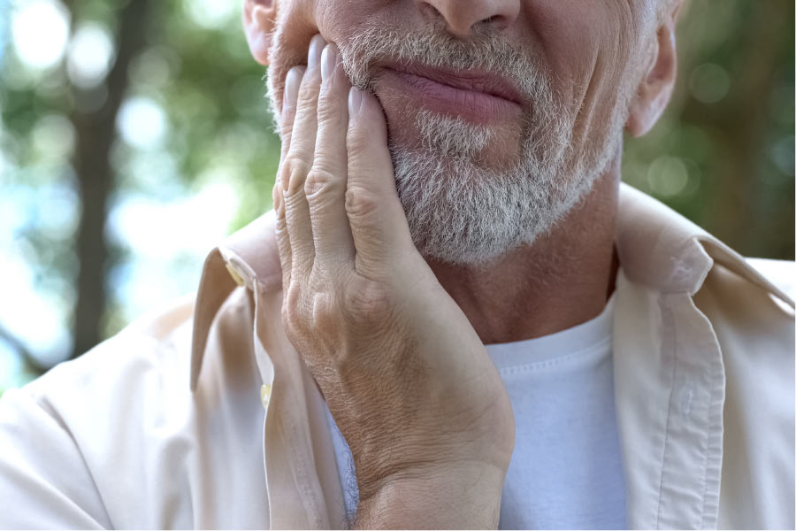 man holds his jaw in pain from an oral infection