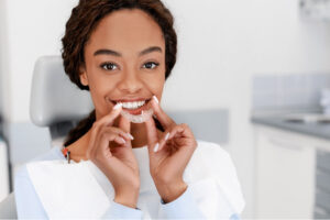 young woman inserts a clear aligner to straighten her teeth