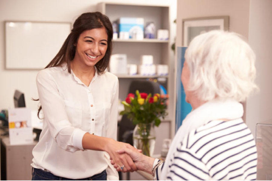 senior woman is greeted by a dental associate at a six month checkup 