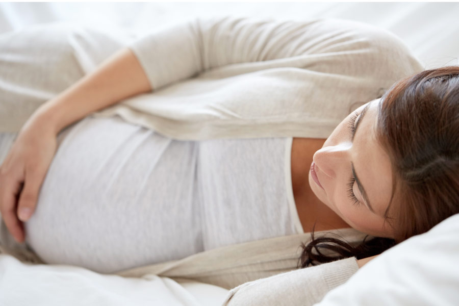 pregnant woman laying on her side holding her belly