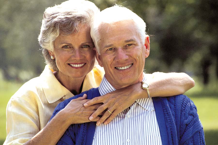 senior couple hug and smile after learning about the benefits of dentures