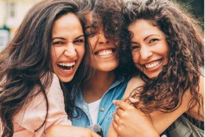 three young women flash their beautiful smiles