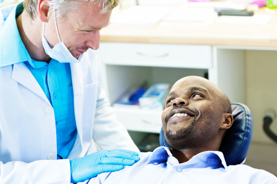 male patient sitting in the dentist chair discusses dental crowns with the dentist