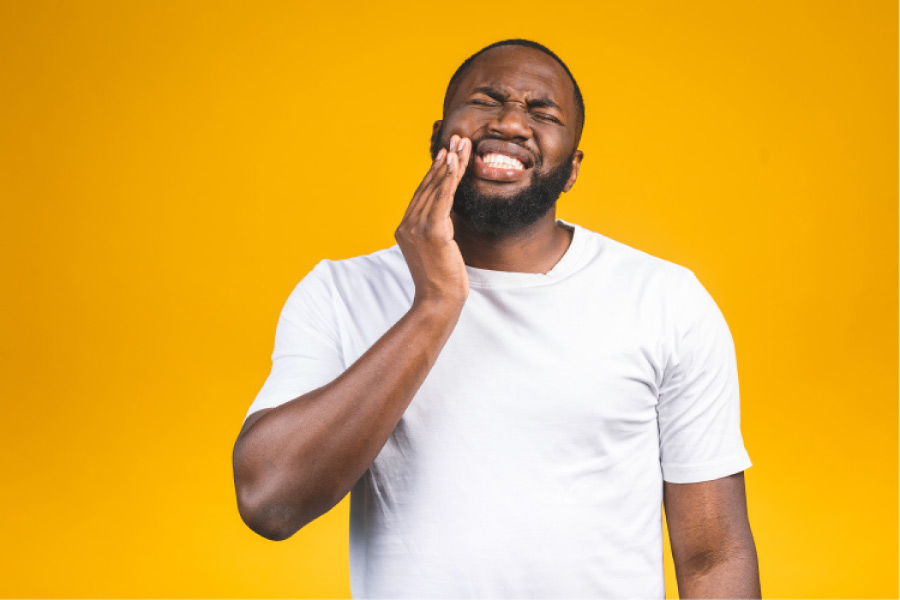 man holds his cheek in pain from a broken tooth