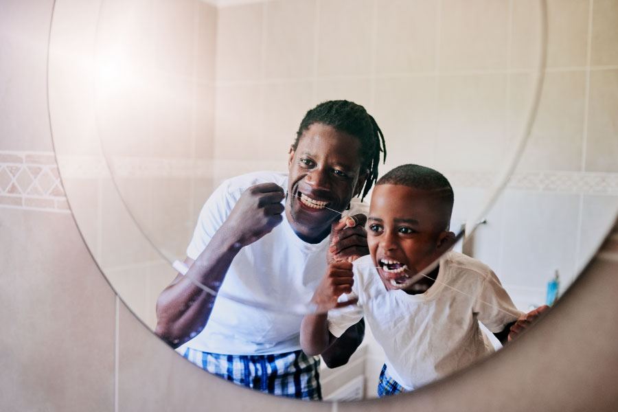 father and young son floss their teeth together