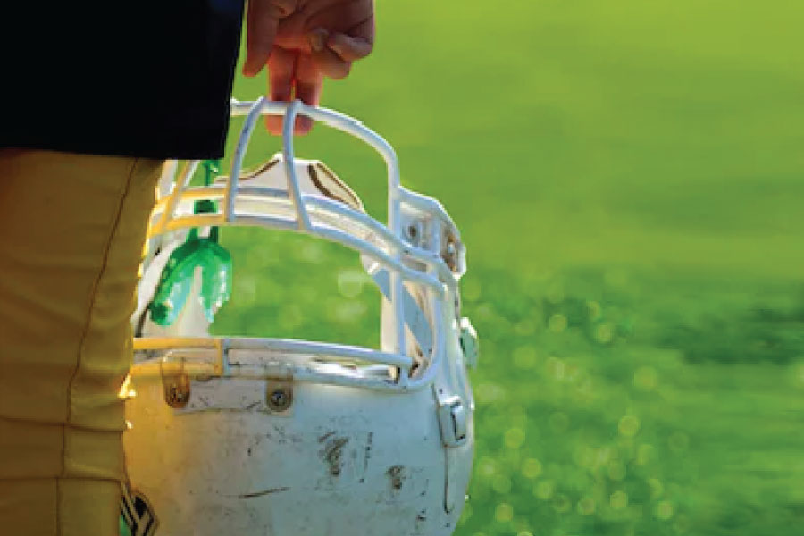 football helmet with a mouthguard attached held by two fingers